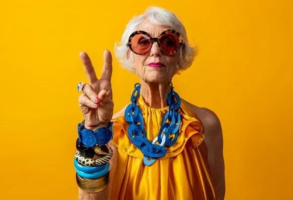 An older woman in bright yellow flashing a peace sign, in the campaign's duotone